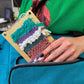 Model placing 1/2 complete mini loom kit for weaving into crafter's deluxe storage bag