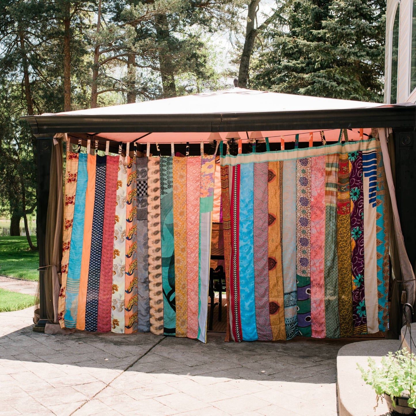 Outdoor sari silk curtains hanging around a pergola.