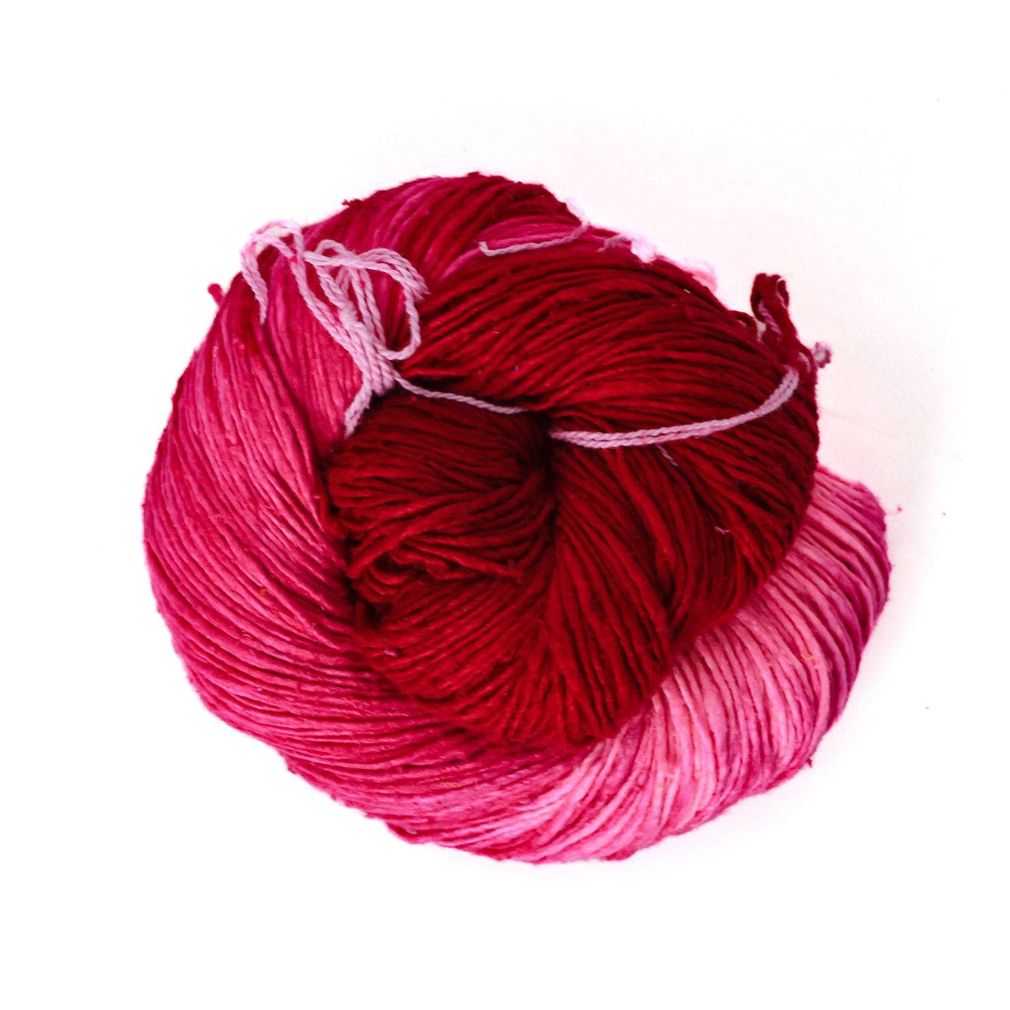 Ombre lace weight silk yarn pink in front of a white background.