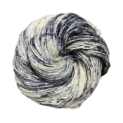 Sport weight silk yarn in Birch Bark (undyed yarn with speckles of black) in front of white background.