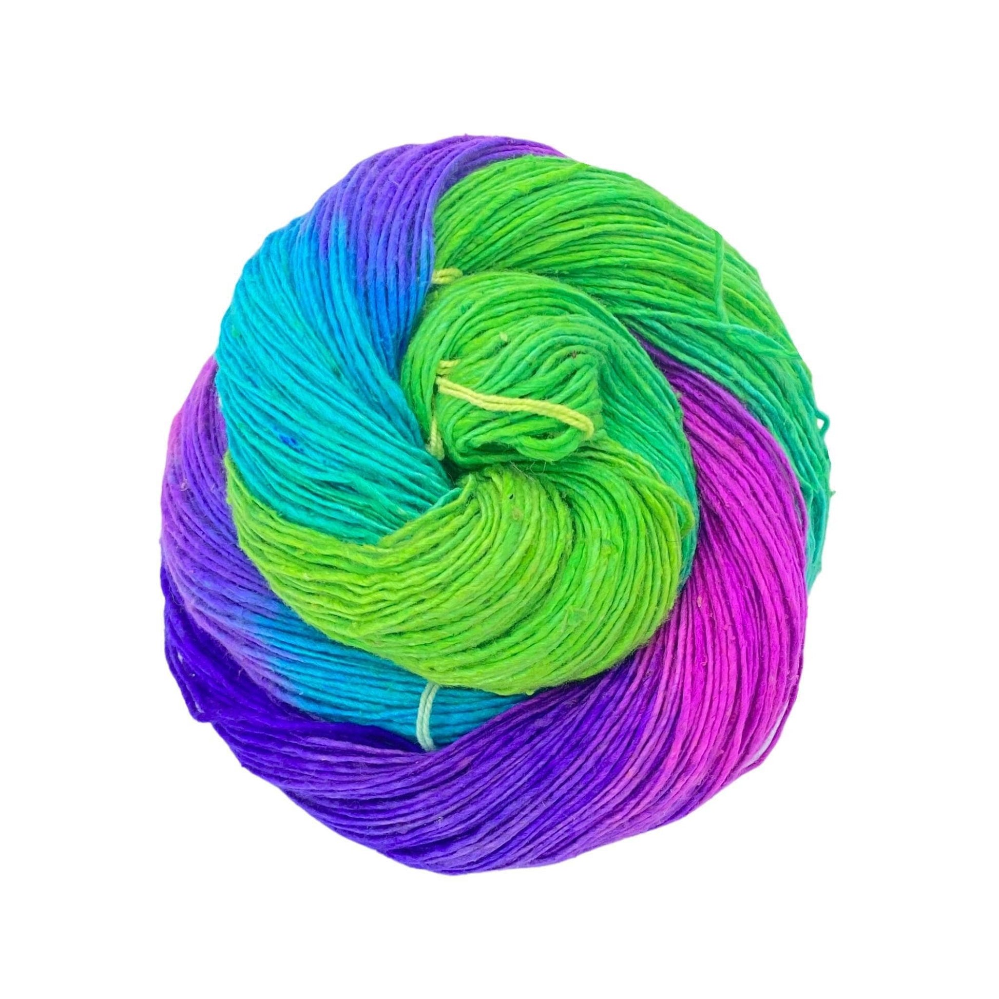 skein of single ply 100% recycled silk yarn in vibrant purple, green, blue, and pink variegated.