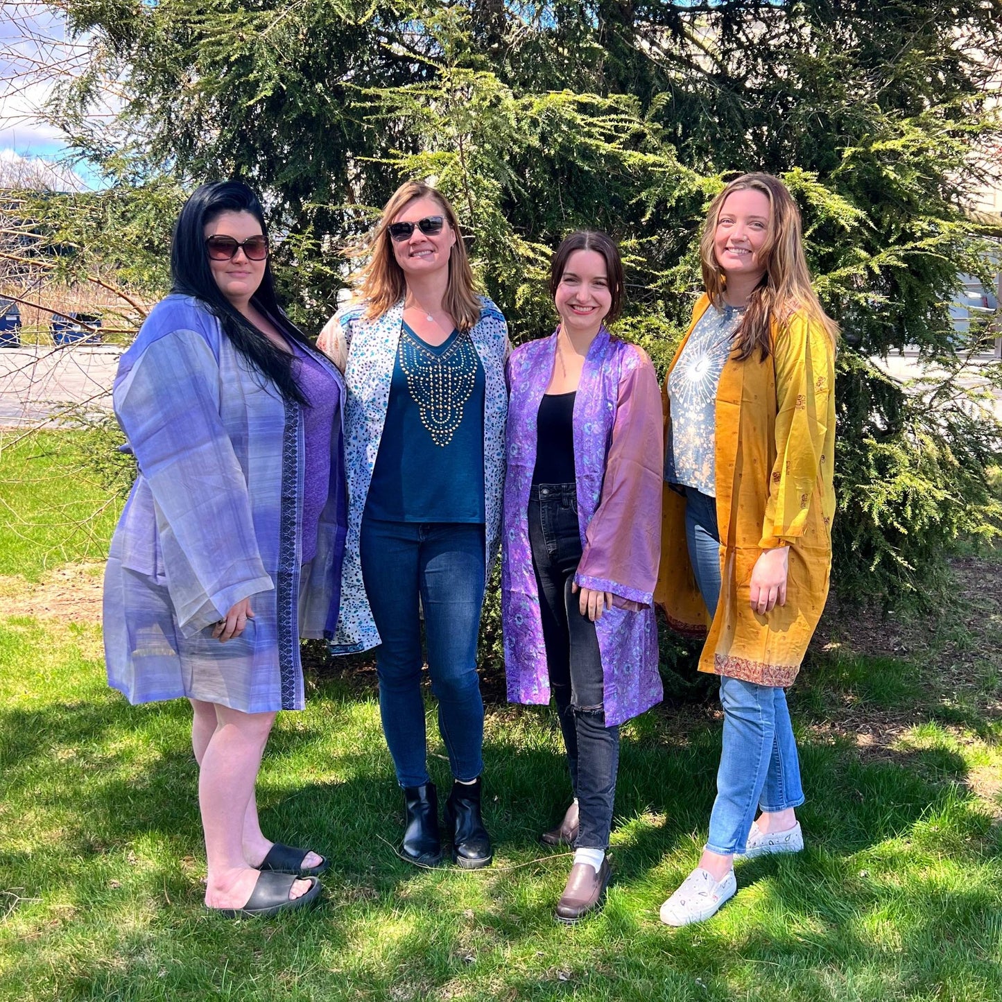 Four model's standing in front of a tree wearing different colored charlotte chic robes. 