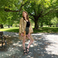 Model is standing in a park wearing a brown short charlotte chic robe. 