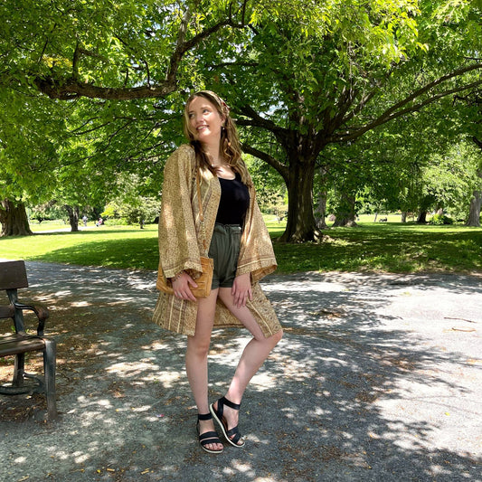 Model is standing in a park wearing a brown short charlotte chic robe.