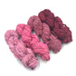 Chiffon Ribbon yarn is the colorway Lipstick on a white background. These colors are light pinks to blush red.