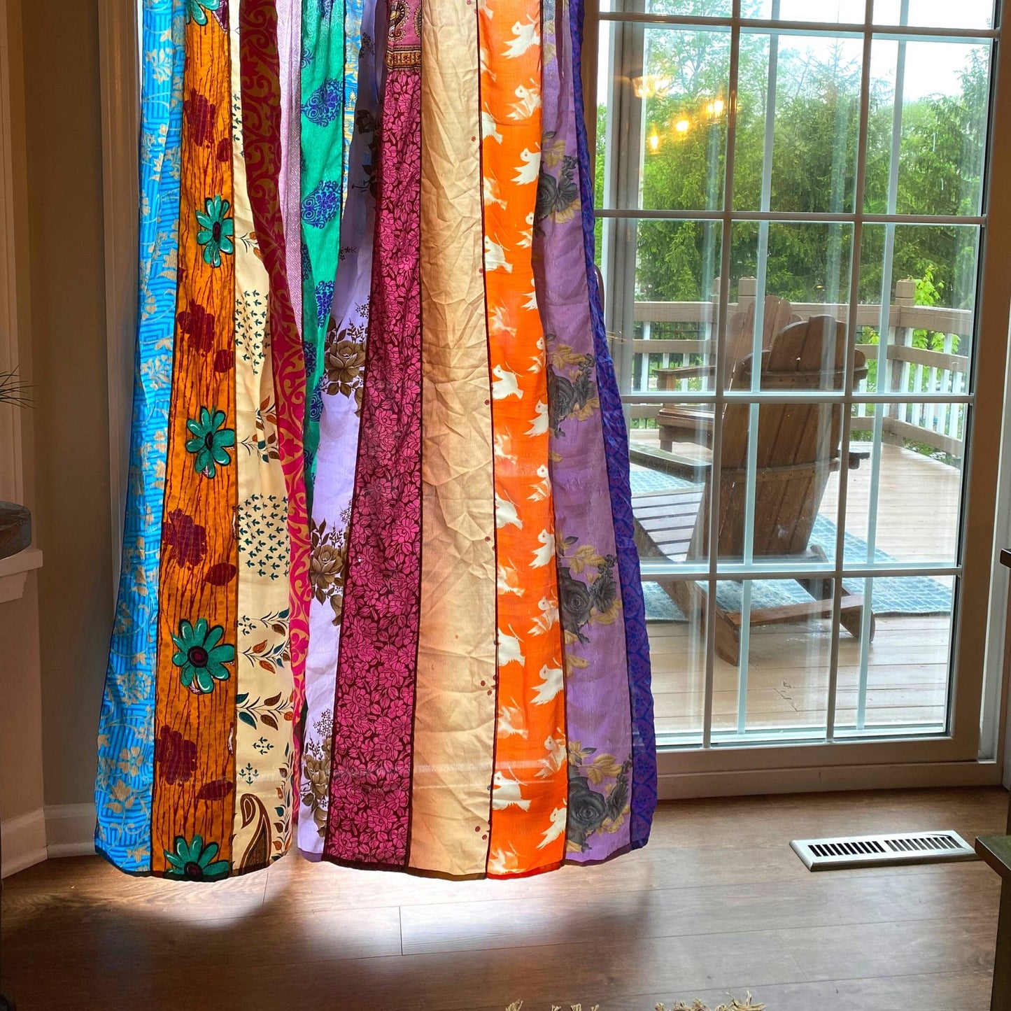 Bottom half of rainbow oasis sari silk curtains blowing in the wind.