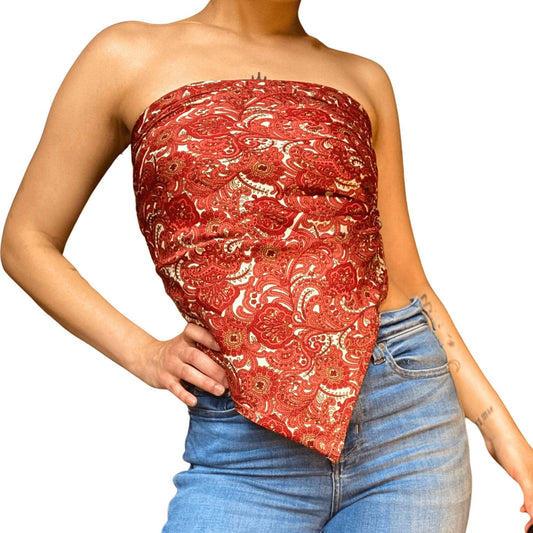 A woman standing on a white background with a Red paisley sari silk scarf top on, paired with blue jeans.