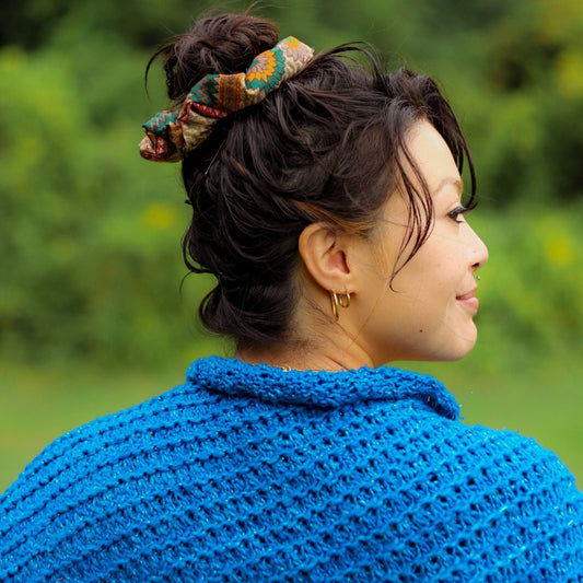 Model has her hair up in a bun wearing a green and orange sari silk scrunchie