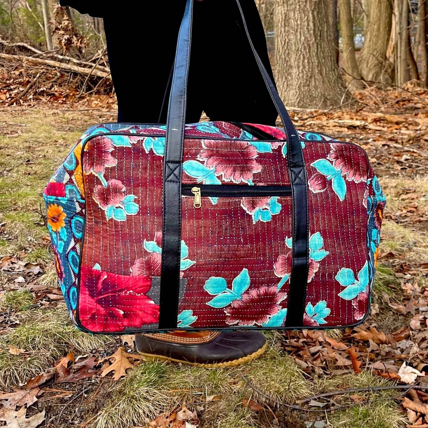 A model holding a purple Kantha Duffle Bag with Light Blue and Lavender Flower Patterns on it.