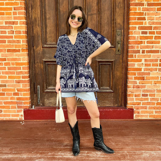 Model is wearing a navy eloise kaftan while standing in front of a wooden door on a brick porch.