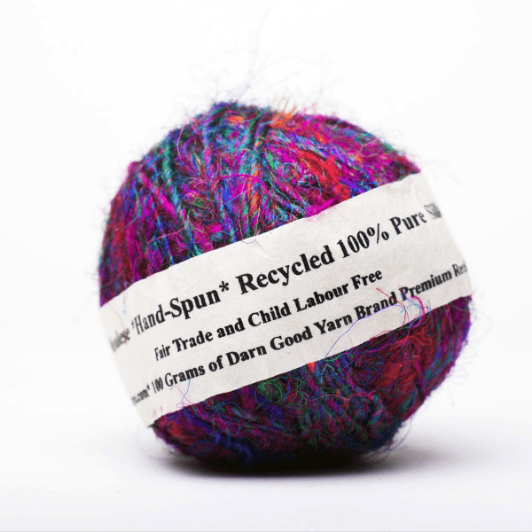 A ball of premium handspun sari silk yarn on a white background, made entirely from reclaimed sari materials.