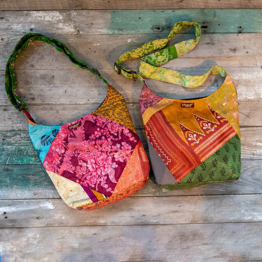 2 one of a kind sari purses laying on a distressed wood surface. Purses are multicolor with a red tag that reads beni.