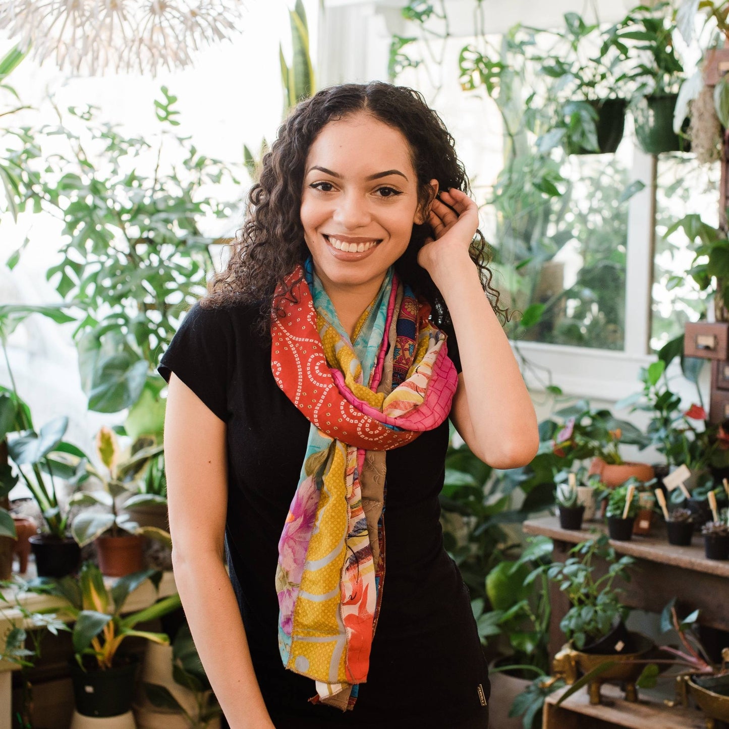 Model is wearing a pink and yellow medley scarf tied knotted-around their neck. 