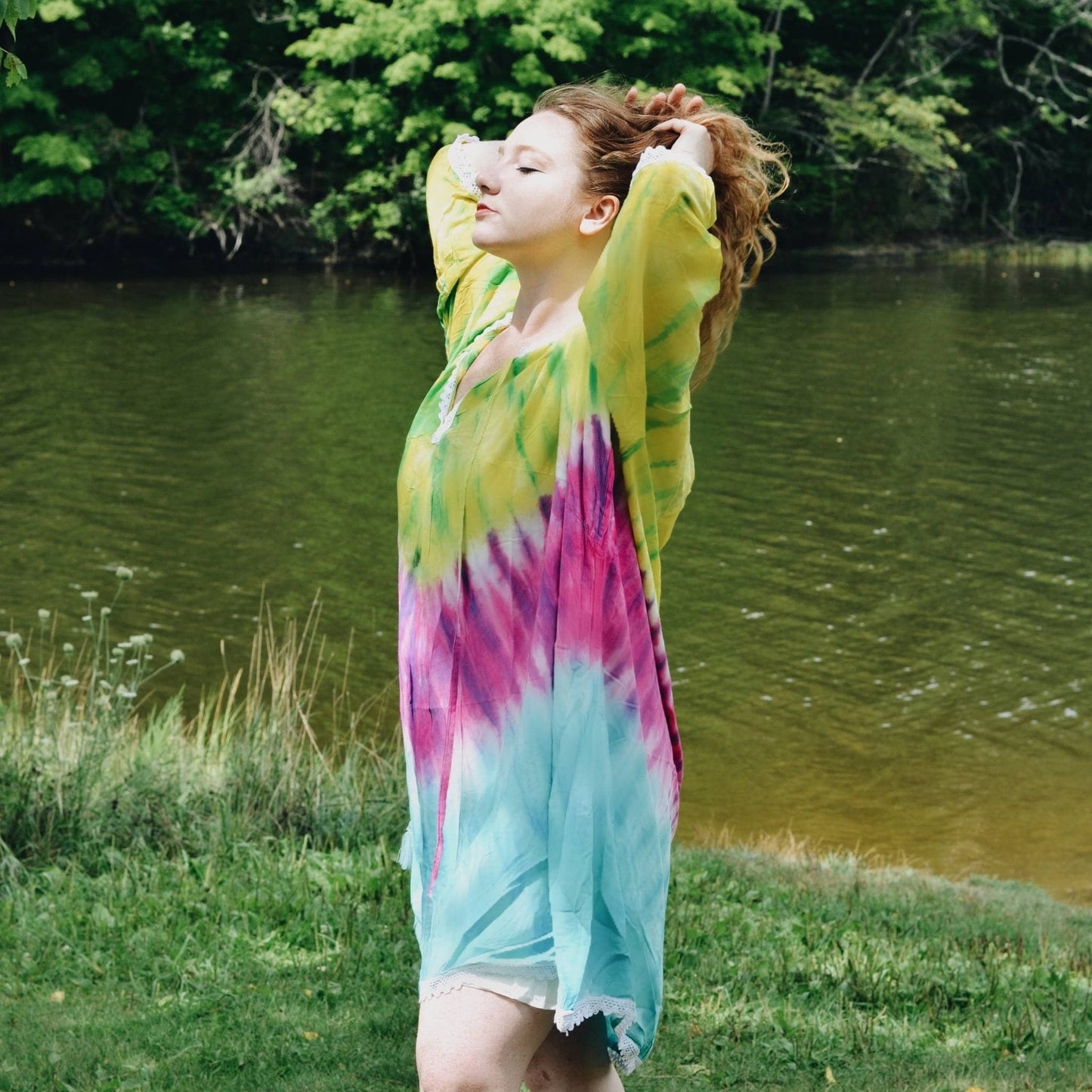 Model is standing by a pond wearing the brillant Tie Dye Cover Up