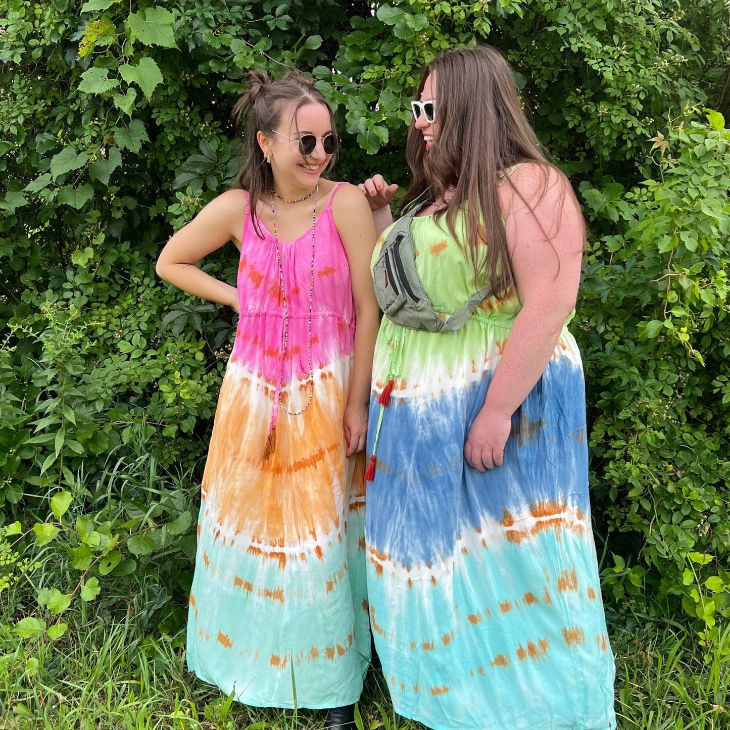 Two models are laughing while wearing the pastel tie dye maxi dresses in both colors blue breeze and rainbow sherbet.