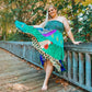 Woman in Goddess size turquoise Sedona Patchwork Dress outside leaning on wooden railing.