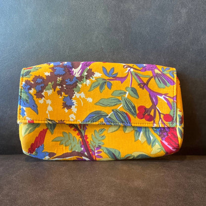 Yellow cotton clutch sitting on a leather booth seat.